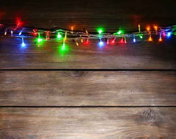 Christmas lights on wooden background — Stock Photo, Image