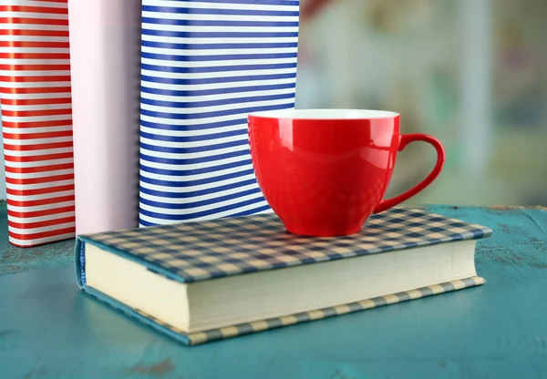 Color cup of tea with books on table, on light blurred background — Stock Photo, Image