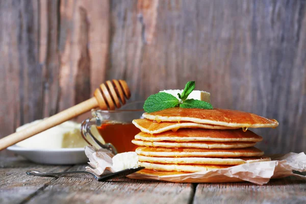 Stack of pancakes with honey and butter on rustic wooden background — Stock Photo, Image