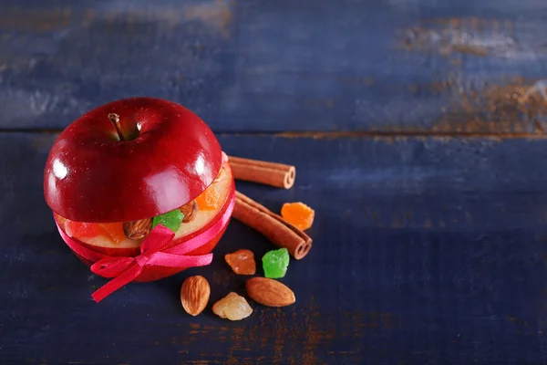 Красное яблоко фаршированное сухофруктами с корицей и миндалем на фоне цвета дерева — стоковое фото