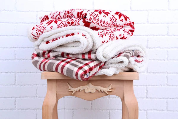 Teplé deky na malý dřevěný stůl a bílé cihlová zeď na pozadí — Stock fotografie