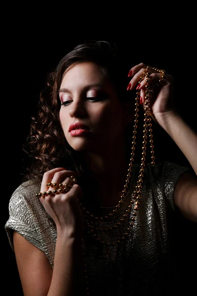 Beau modèle avec des perles dans les mains sur fond sombre — Photo