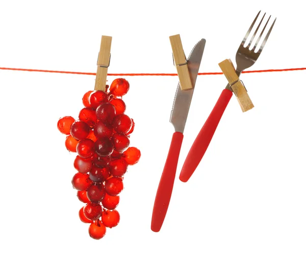 Widelec, nóż i winogron wiszące od bielizny na białym tle na białym tle — Zdjęcie stockowe