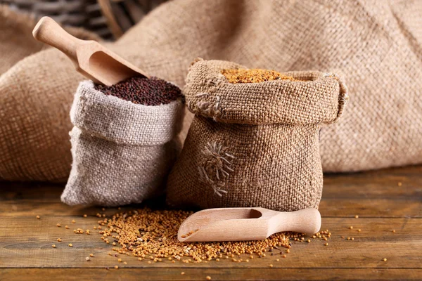 Semillas de mostaza en bolsas sobre fondo de madera —  Fotos de Stock