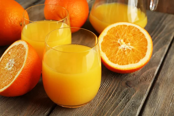 Glas Orangensaft mit Scheiben auf rustikalem Holztischhintergrund — Stockfoto