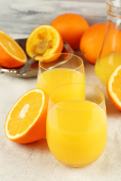 Glass of orange juice with slices on metal tray on table and color wooden wall background — Stock Photo, Image