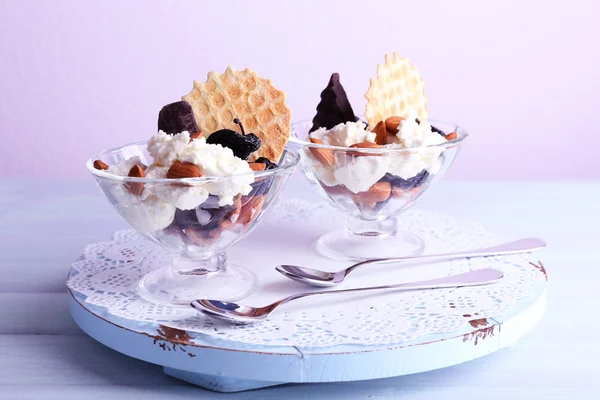 Dessert with prunes in glass bowls on color wooden table background — Zdjęcie stockowe