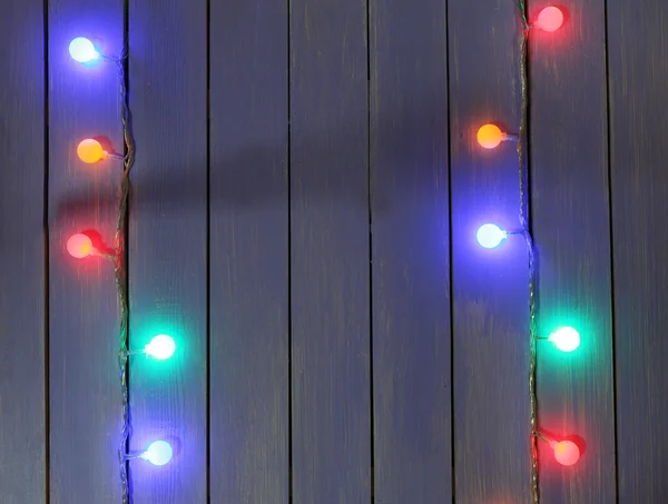 Colorful Christmas lights on wooden planks background — Stock Photo, Image