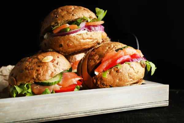 Sandwiches con salmón en bandeja, sobre fondo oscuro — Foto de Stock