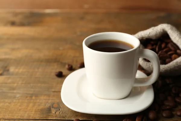 Xícara de café com feijão em fundo de madeira rústica — Fotografia de Stock