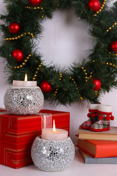 Decoración navideña con guirnalda, velas y cajas de regalo en estante sobre fondo de pared blanco —  Fotos de Stock