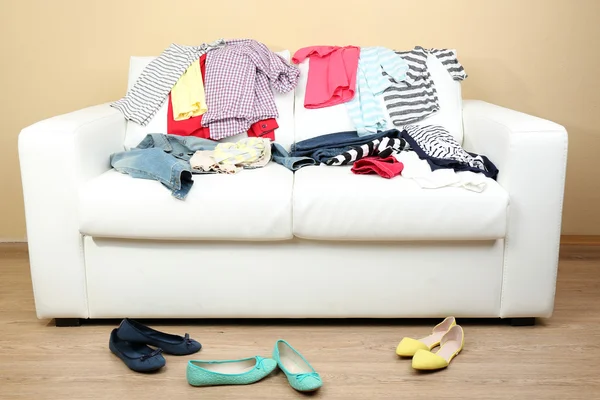 Beyaz kanepe ve kadın ayakkabı hafif duvar arka plan üzerinde renkli giyim