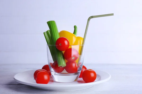 Légumes en verre avec tube sur plaque et sur fond de planches en bois de couleur — Photo