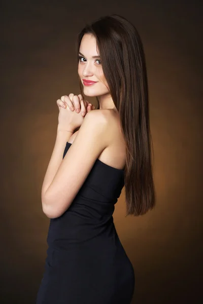 Beautiful young woman with long hair on dark brown background — Stock Photo, Image