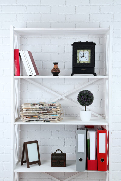Bookshelves with books and decorative objects on brick wall background
