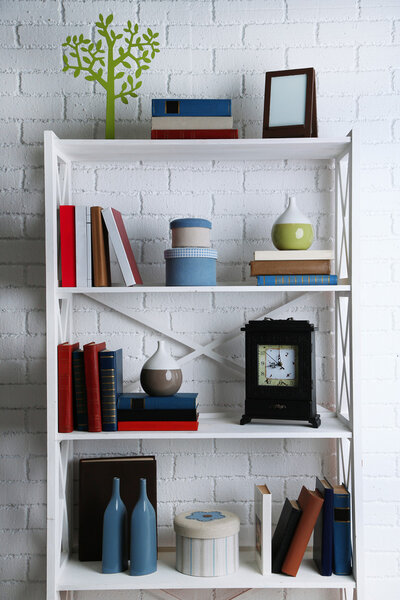 Bookshelves with books and decorative objects on brick wall background