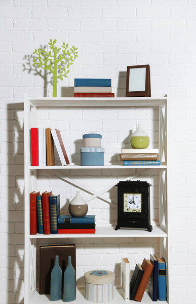 Bookshelves with books and decorative objects on brick wall background