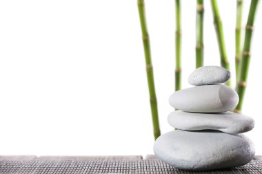 Natürmort Spa beyaz izole bambu sopalarla bambu mat yüzey üzerinde taşlar