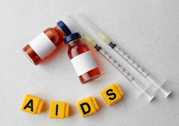 AIDS λέξη και ιατρικό εξοπλισμό επάνω ελαφρύς υπόβαθρο — Φωτογραφία Αρχείου