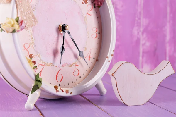 Beautiful vintage clock with decorative bird on table on wooden background — Stock Photo, Image