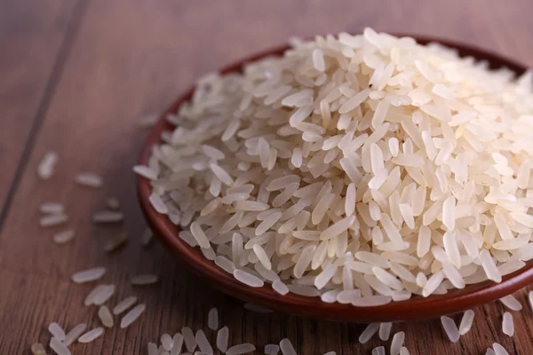 Grain of rice on plate on wooden background — Stock Photo, Image