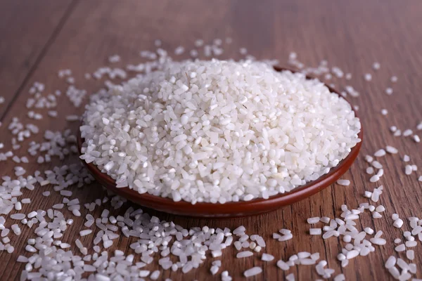 Grain de riz sur assiette sur fond en bois — Photo