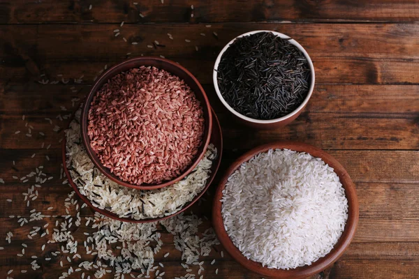 Diferentes tipos de arroz en cuencos sobre fondo de madera — Foto de Stock