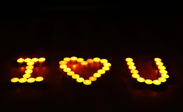 Palabras que TE AMO formadas por velas encendidas sobre fondo oscuro — Foto de Stock