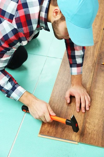 Trabalhador de carpinteiro instalando piso laminado — Fotografia de Stock