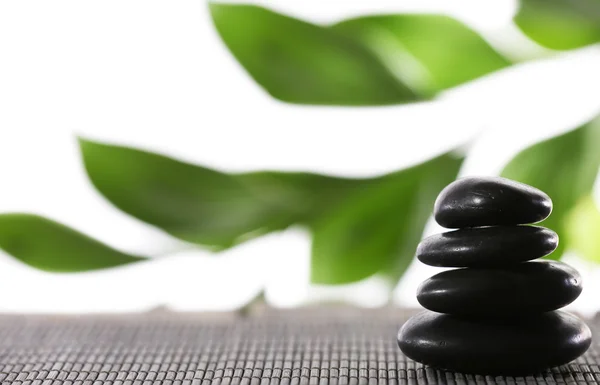 Stack of spa stones on bamboo mat surface with green leaves isolated on white — Stock Photo, Image