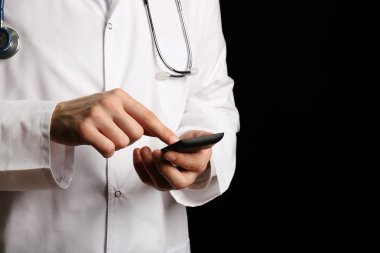 Hareket eden telefon ile siyah arka plan üzerine çalışan doktor