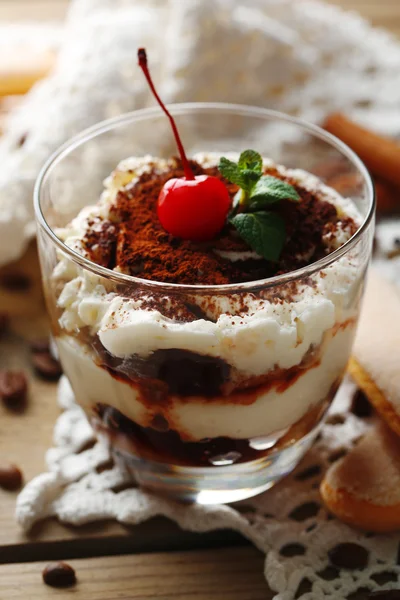 Tasty tiramisu dessert in glass, on napkin, on wooden background — Stock Photo, Image