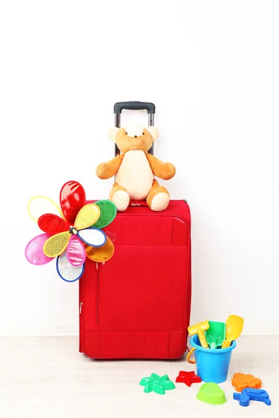 Red suitcase with toy flower and child toys isolated on white — Stock Photo, Image
