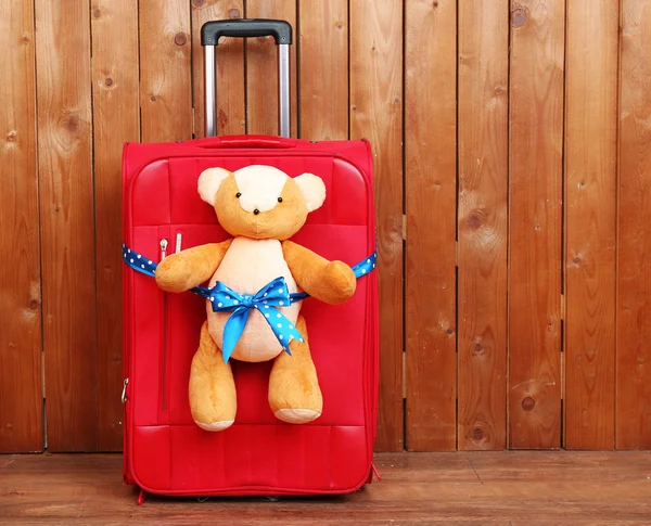 Suitcase with teddy bear on wooden planks background — Stock Photo, Image