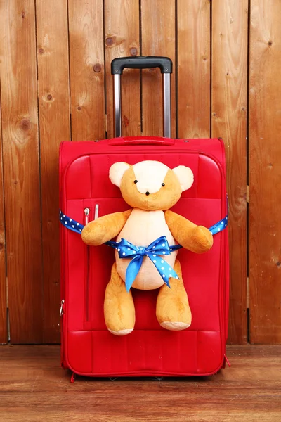 Suitcase with teddy bear on wooden planks background — Stock Photo, Image