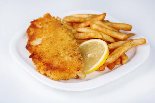 Breaded fried fish fillet and potatoes with sliced lemon on plate isolated on white — Stock Photo, Image