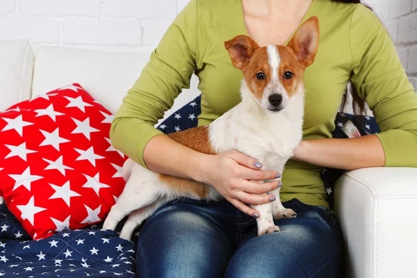 Woman sitting on sofa with cute dog, close-up — Stock Photo, Image