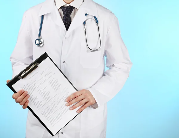 Médico trabajando con documentos sobre fondo azul —  Fotos de Stock