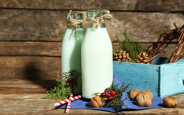 Bottiglie di latte fresco con decorazione naturale, su sfondo di legno — Foto Stock