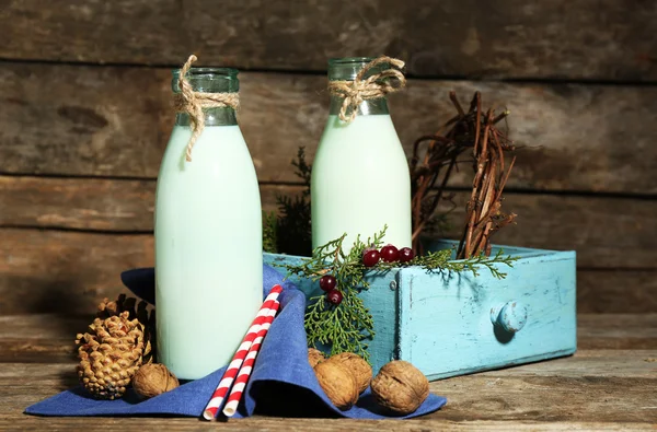 Bottles of fresh milk with natural decor, on wooden background — Stock Photo, Image
