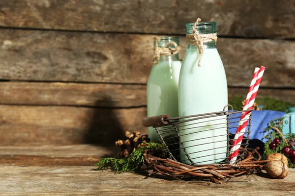 Bottles of fresh milk with natural decor, on wooden background — Stock Photo, Image