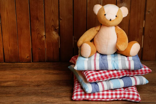 Bear speelgoed op kussens op houten achtergrond — Stockfoto