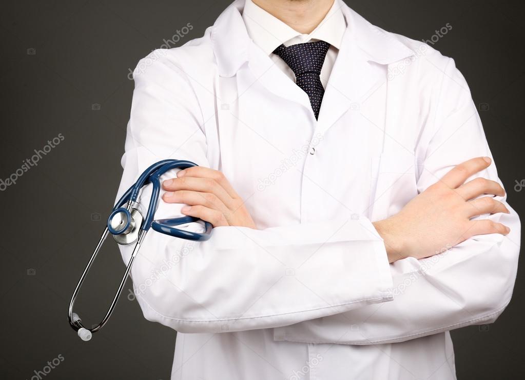 Male doctor with stethoscope on grey background