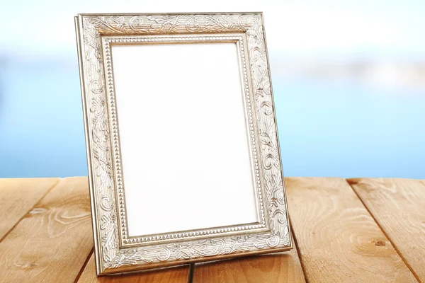 Moldura da foto na mesa de madeira no fundo claro — Fotografia de Stock