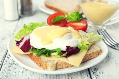 Yumurta Benedict ile tost ve ahşap masa üzerinde tabakta domates