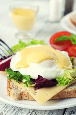 Yumurta Benedict ile tost ve ahşap masa üzerinde tabakta domates