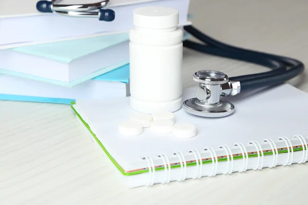 Stéthoscope médical avec livres et tablette sur table en bois — Photo