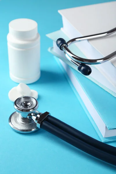 Orvosi sztetoszkóppal, könyvek és kék alapon tablet — Stock Fotó