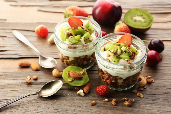 Friska skiktad dessert med müsli och frukt på bord — Stockfoto