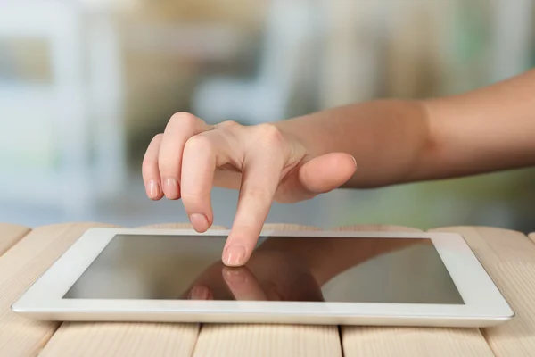 Χέρι χρησιμοποιώντας tablet Pc σε ξύλινο τραπέζι και ανοιχτό φόντο θολή — Φωτογραφία Αρχείου